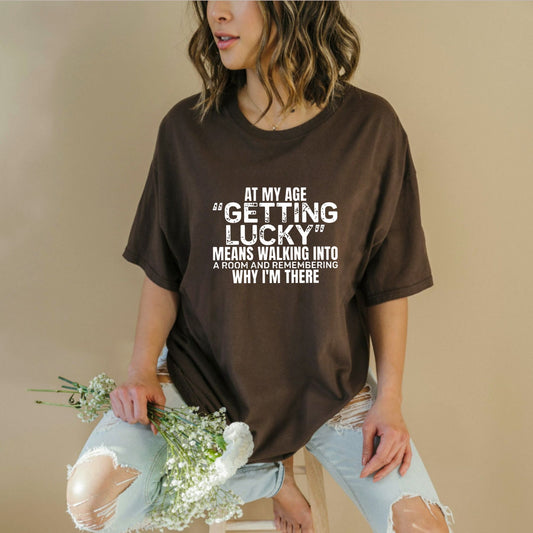 "At My Age Getting Lucky" Funny T-Shirt – Sarcastic Aging Humor Graphic Tee, Unisex Cotton Shirt - Teezioo
